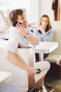 Young couple using mobile phones in a cafe. Shallow DOF, focus o